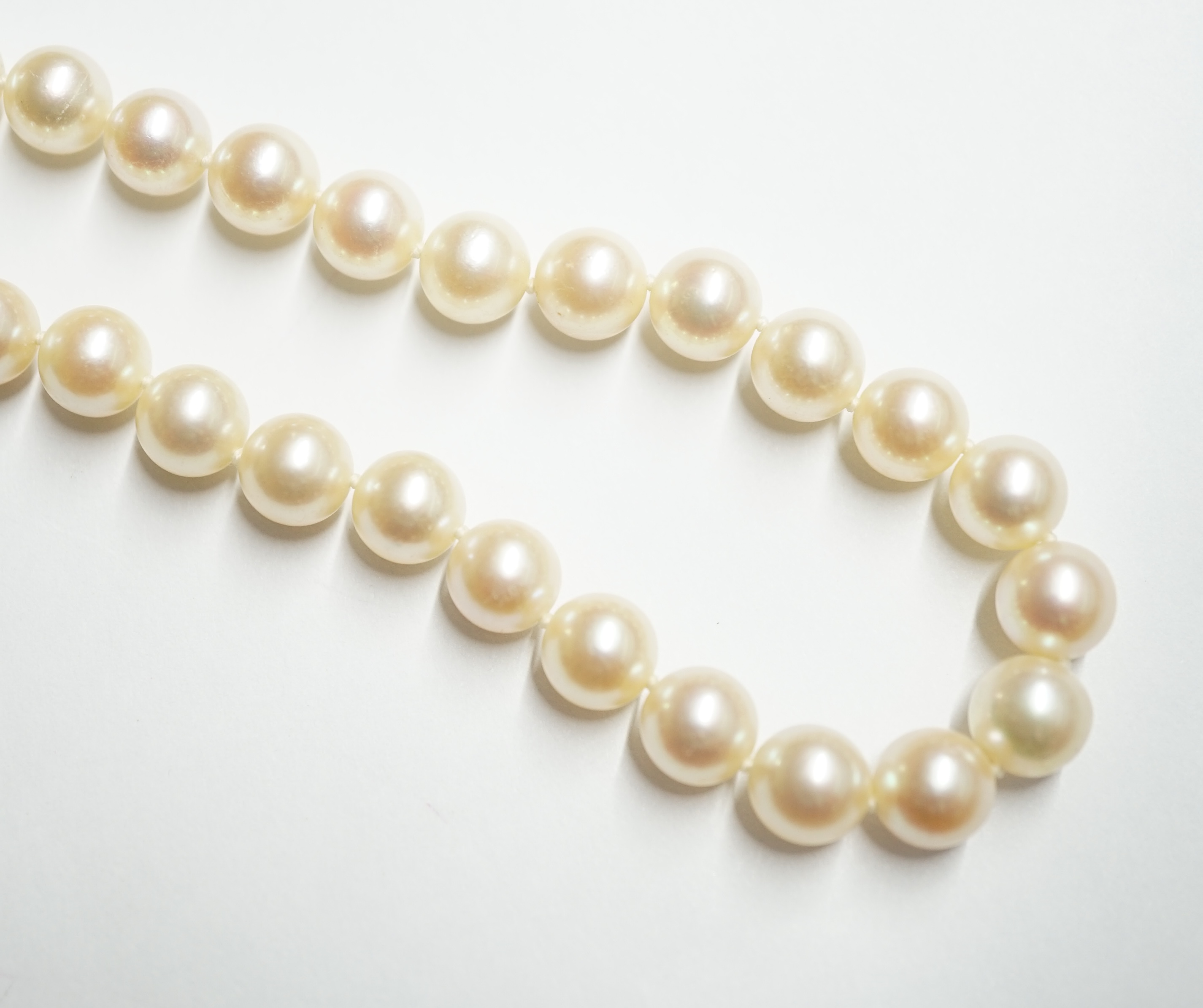 A single strand cultured pearl necklace, with French white metal (18ct mark), sapphire, diamond and cultured pearl set clasp, bearing the signature 'Cartier', 60cm. Condition - fair